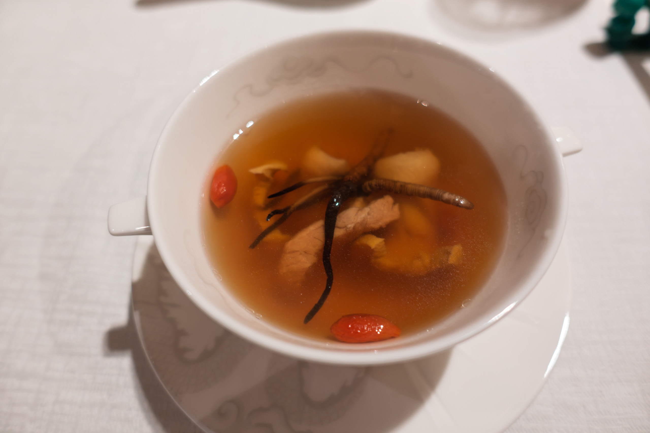 A clear double-boiled soup in a white bowl