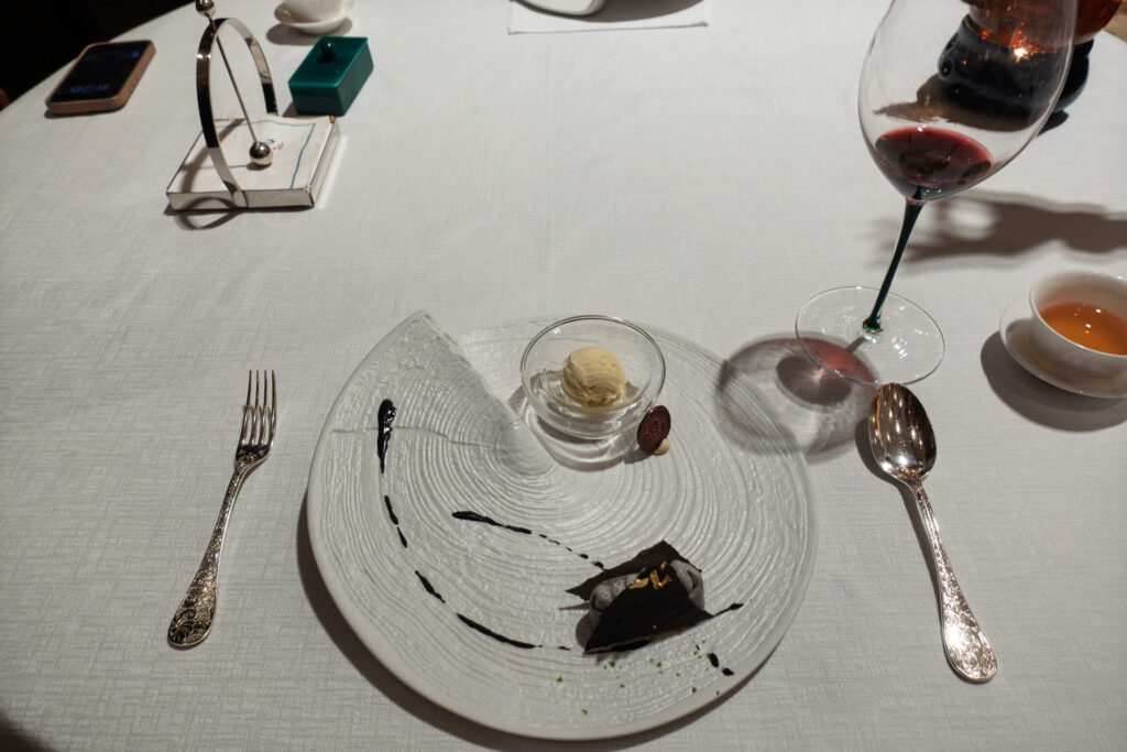 The end of the meal: a cleared plate, silver cutlery and a glass of red wine