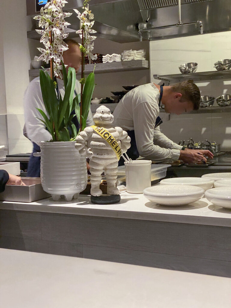 The kitchen at Jônt with a Michelin figurine standing on the pass, cooks working behind