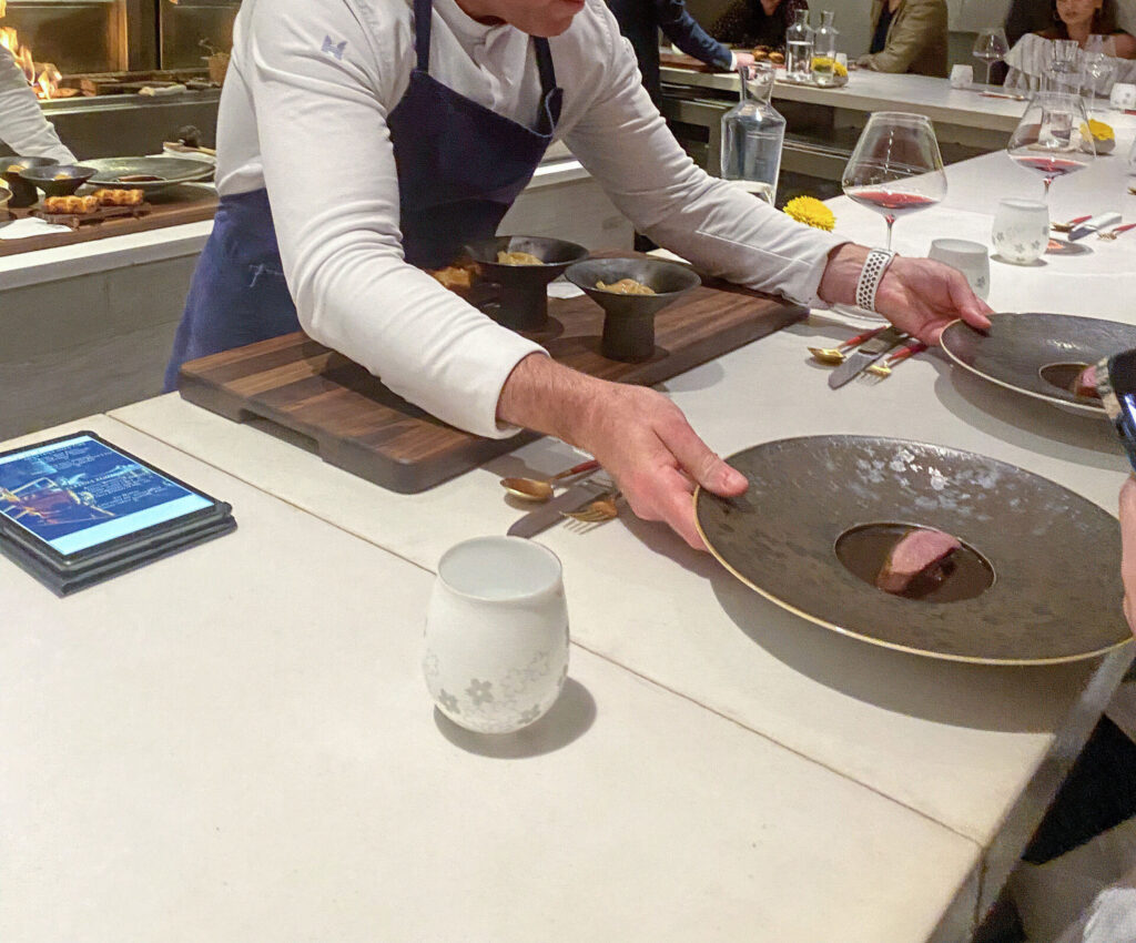 Cooks plating a row of dishes along the pass