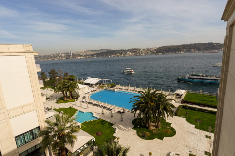The outdoor pool and gardens seen from above, ferries crossing the Bosphorus beyond