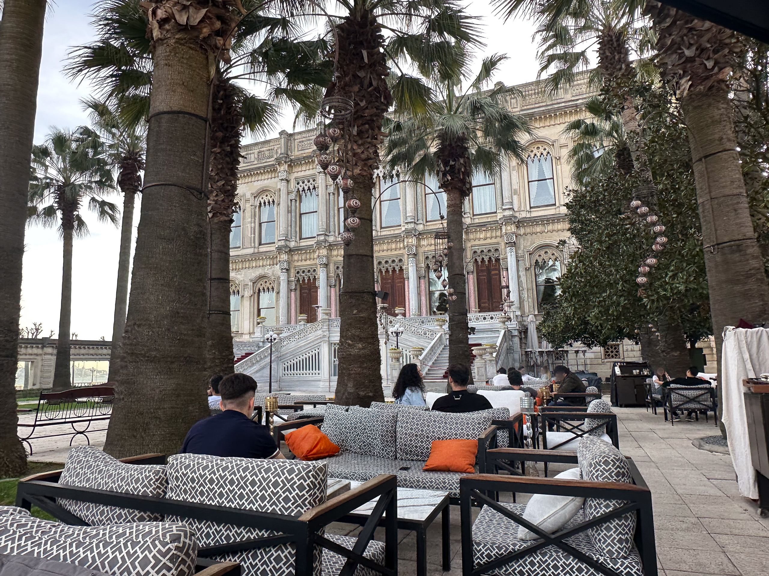 The ornate palace facade seen through palm trunks from the terrace cafe