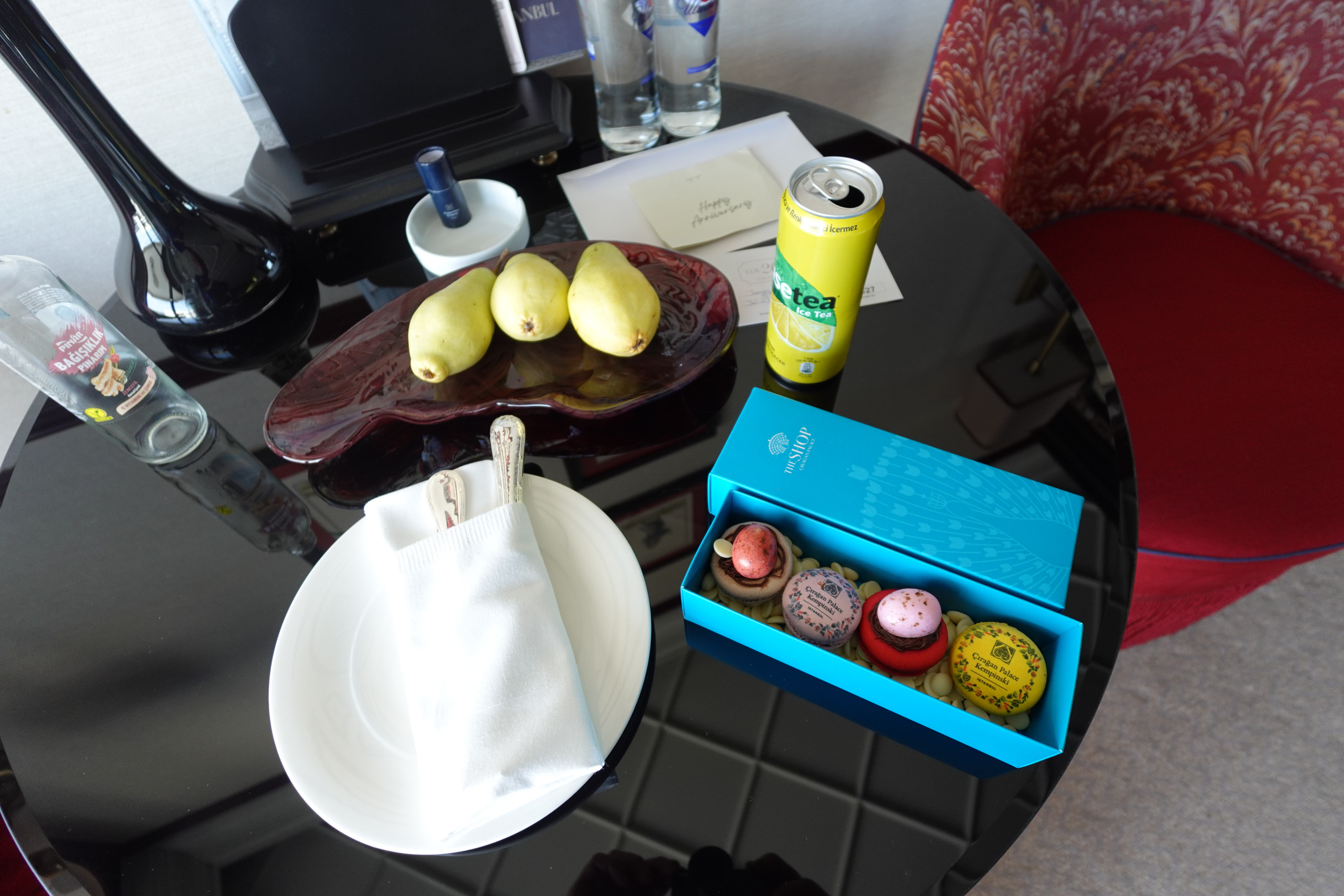 A box of macarons, a bowl of lemons and a drink laid out on the desk