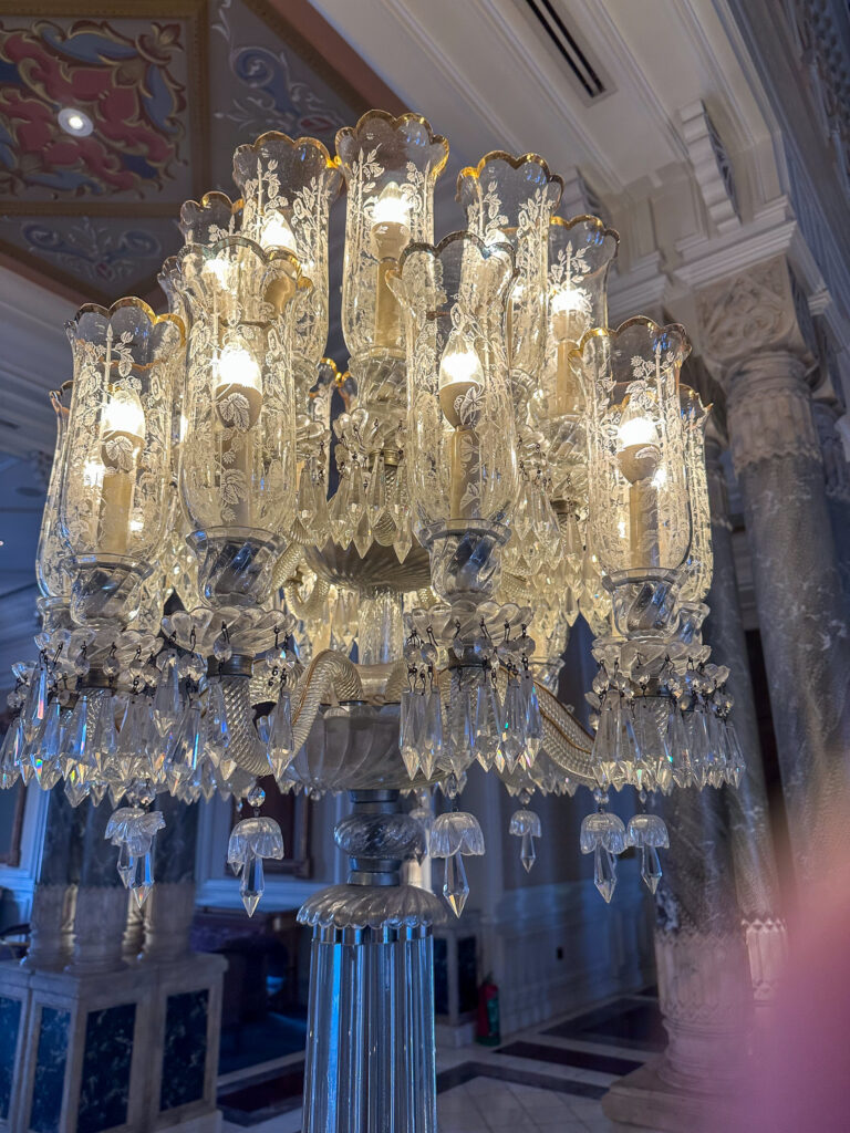 A crystal chandelier in the palace, tiers of glass against the gilding