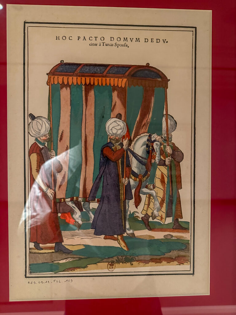 An Ottoman miniature in its frame on a deep red wall
