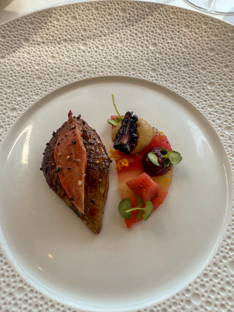 A charred slice with small vegetables, watermelon and olives
