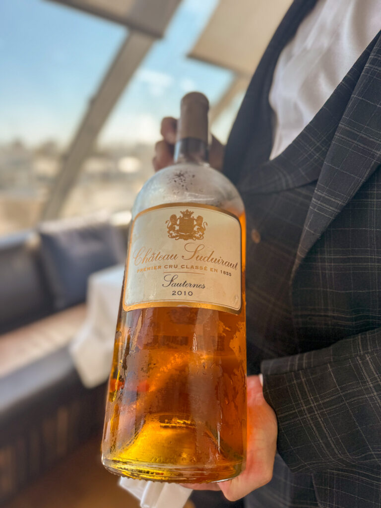 A bottle of Sauternes held up with the Paris rooftops and the Eiffel Tower behind
