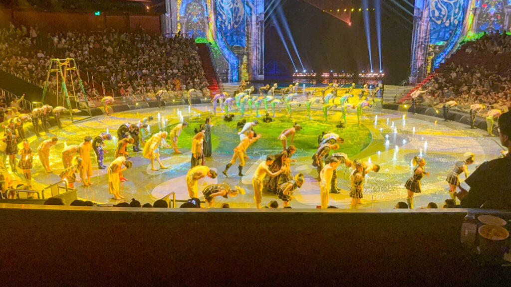 The full company on the drained stage under yellow light
