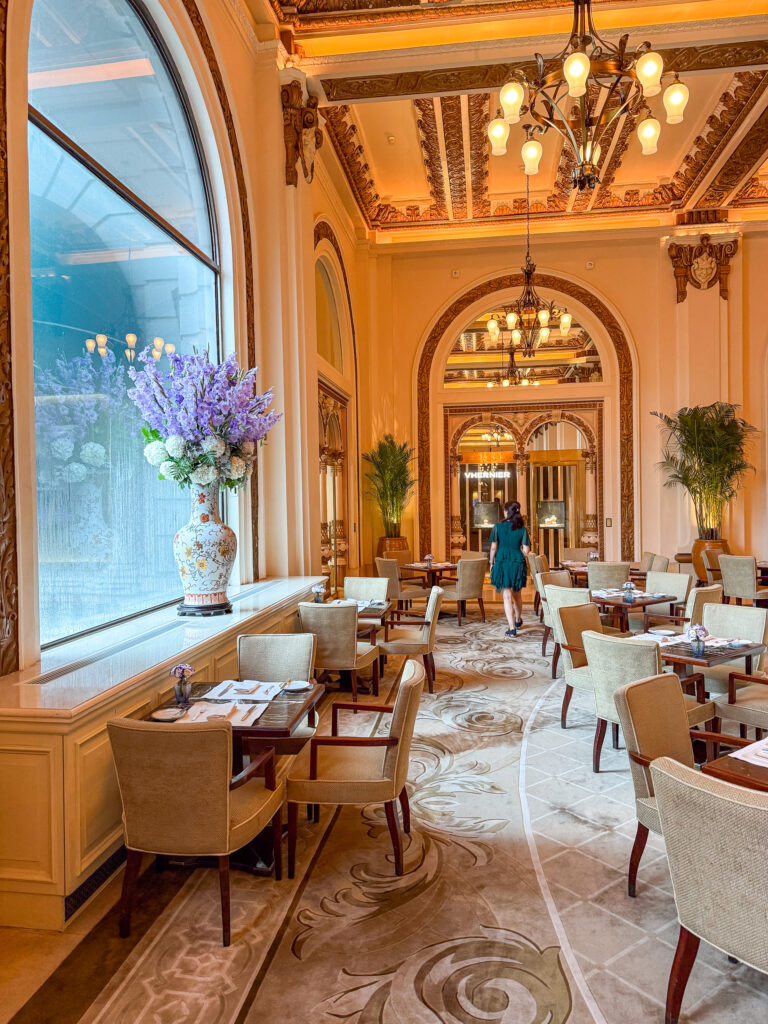 Armchairs beneath the arched windows of the lobby, a chandelier above