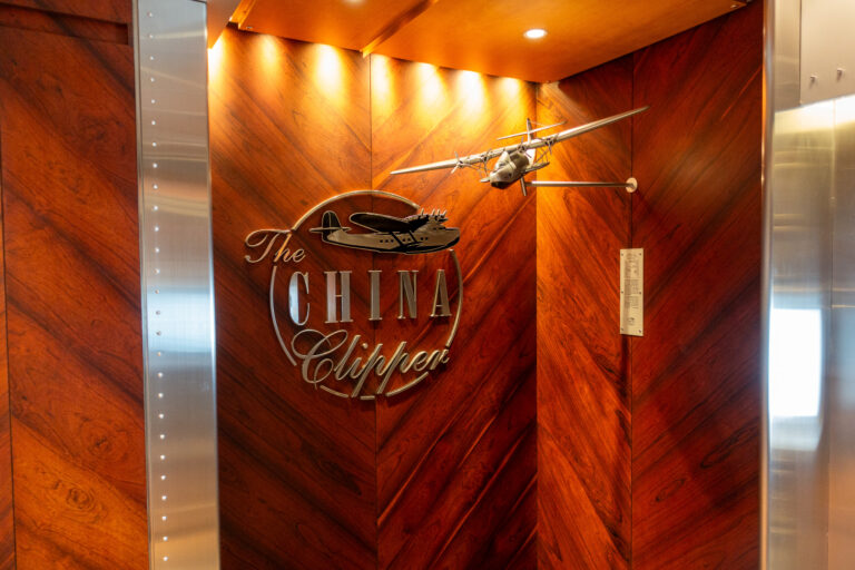 A model flying boat mounted on a burr-walnut wall beside the lift