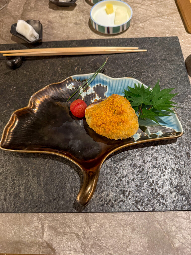 A single piece of urchin on a leaf-shaped dish over stone