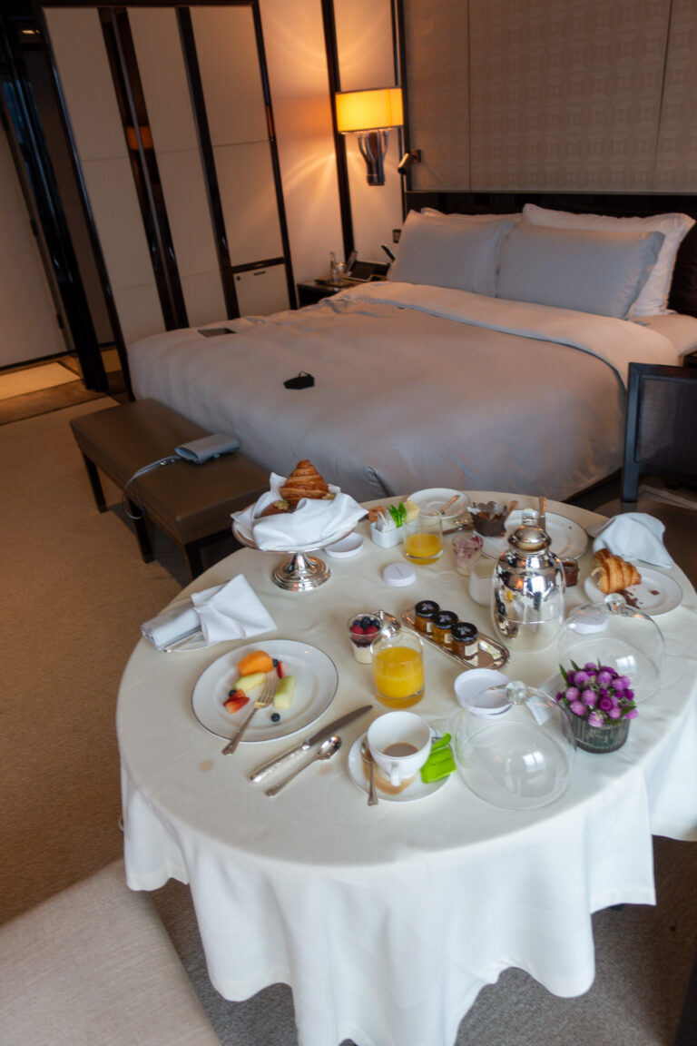 A room-service table laid for breakfast beside the made bed