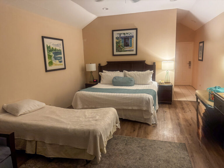 Twin beds made up in white, framed prints on the wall behind them