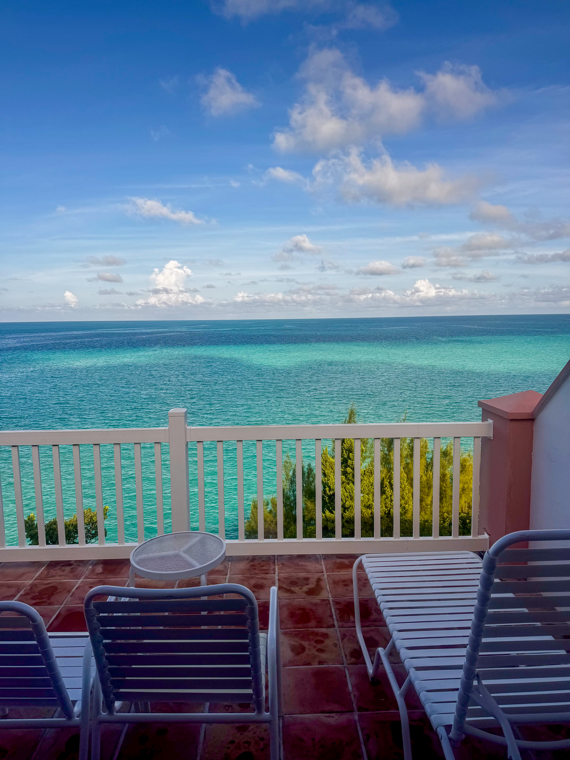 Blue chairs at the rail, the water running out in bands of turquoise