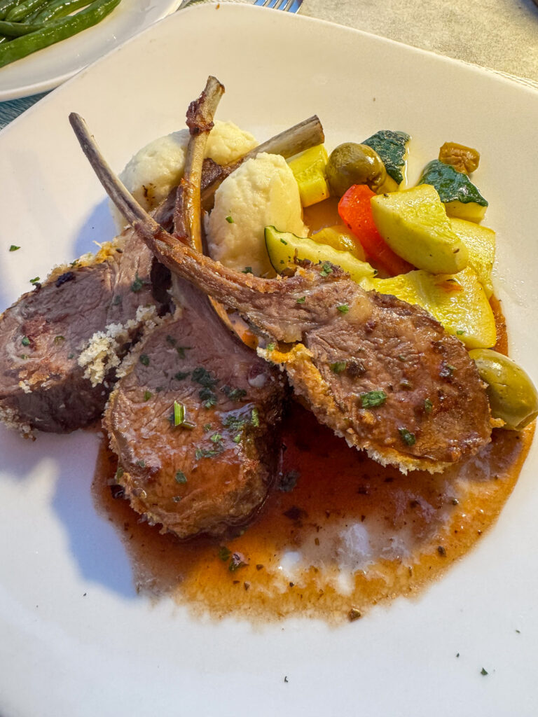 Lamb chops standing in their sauce with vegetables alongside