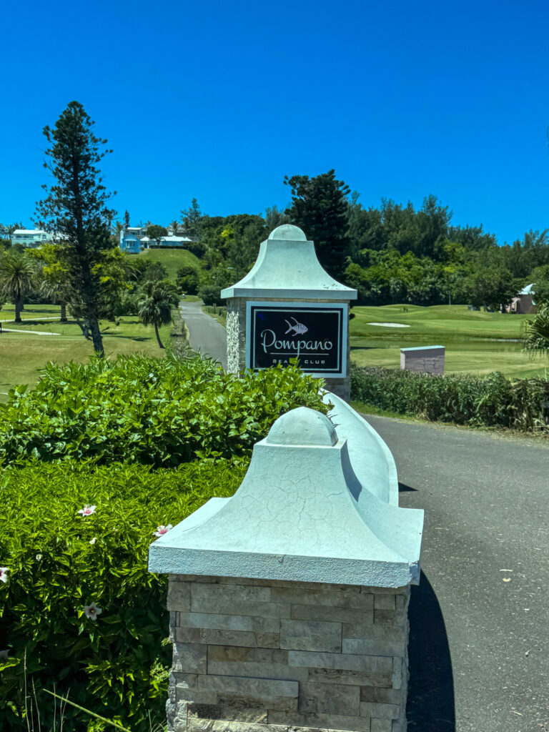 A stone gatepost with the club's sign, the course behind it
