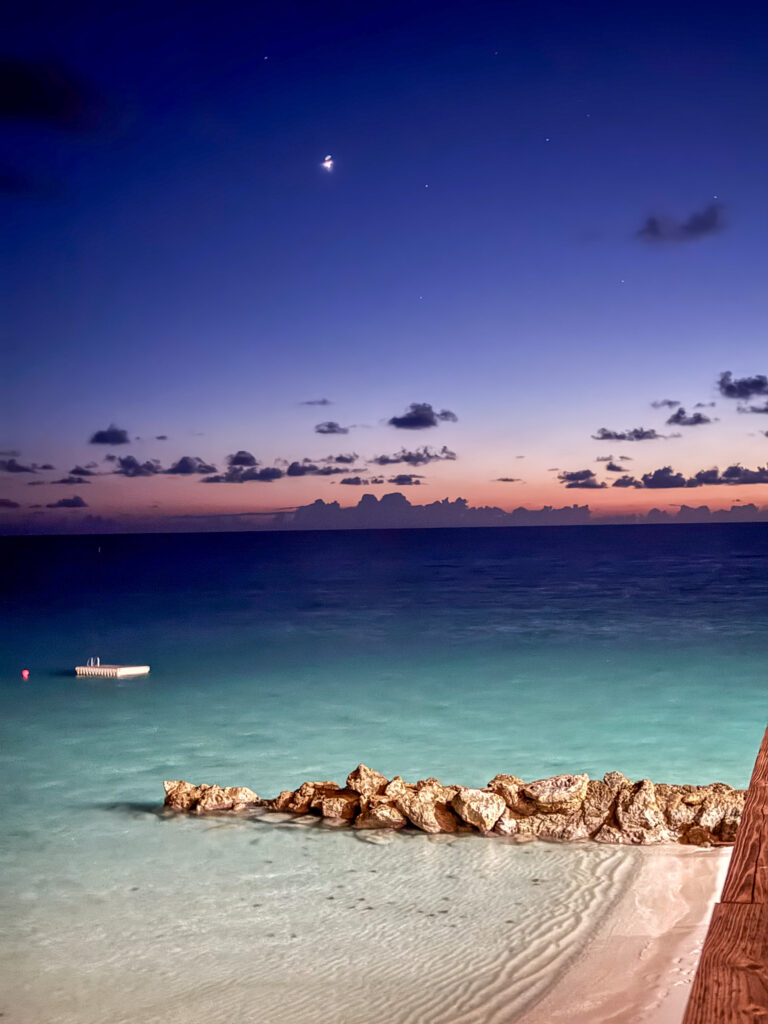 A boat moored off the breakwater as the light goes, the moon already up