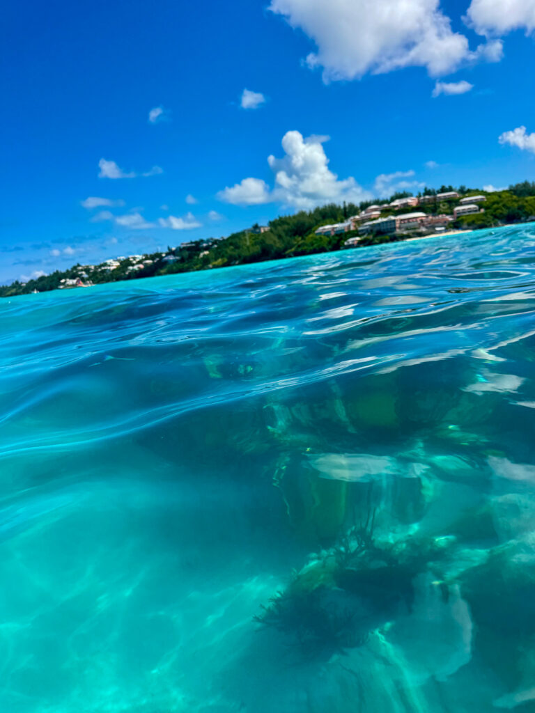 The waterline across the lens — sky above, sand and water below
