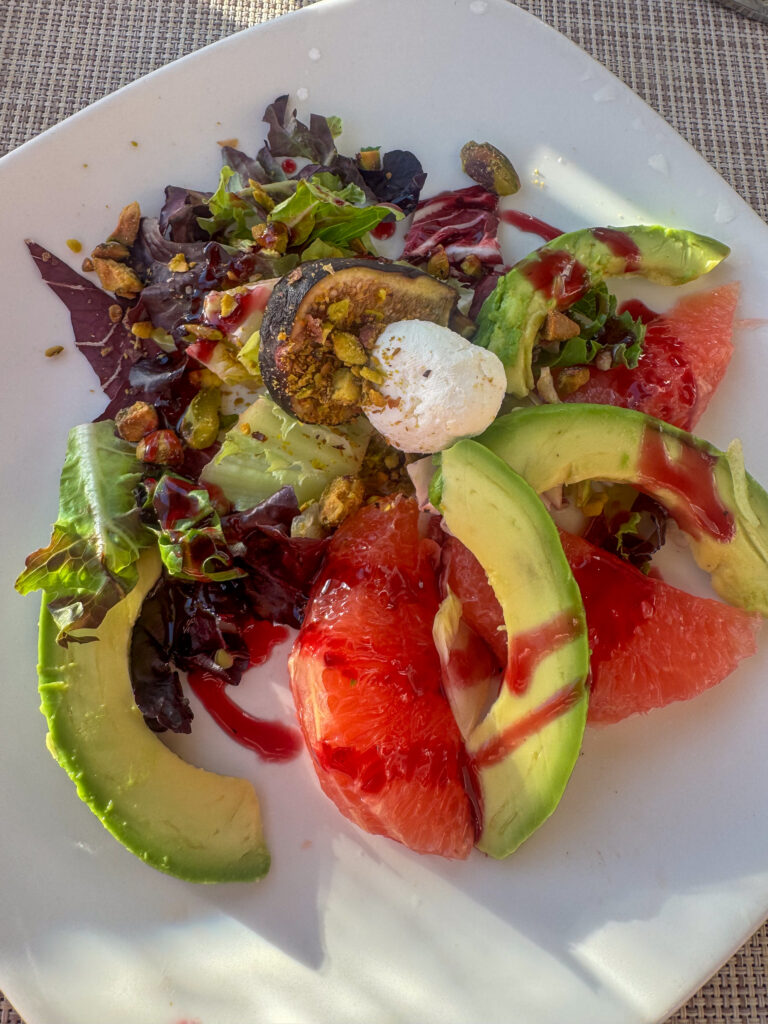 Avocado, tomato and leaves piled on a white plate