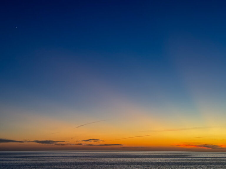 The sky grading from orange to blue over a flat sea