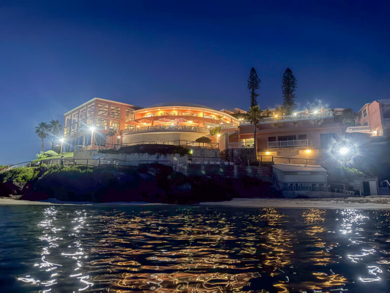 The buildings lit along the water, reflections running out towards the lens
