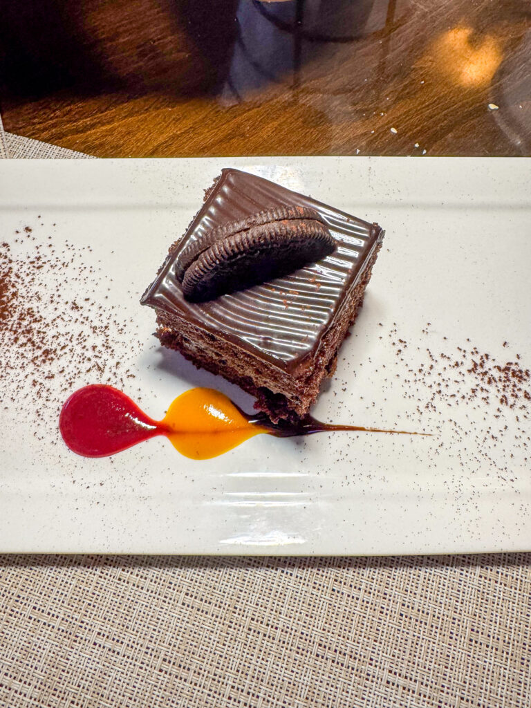 A chocolate dessert with two sauces drawn beside it