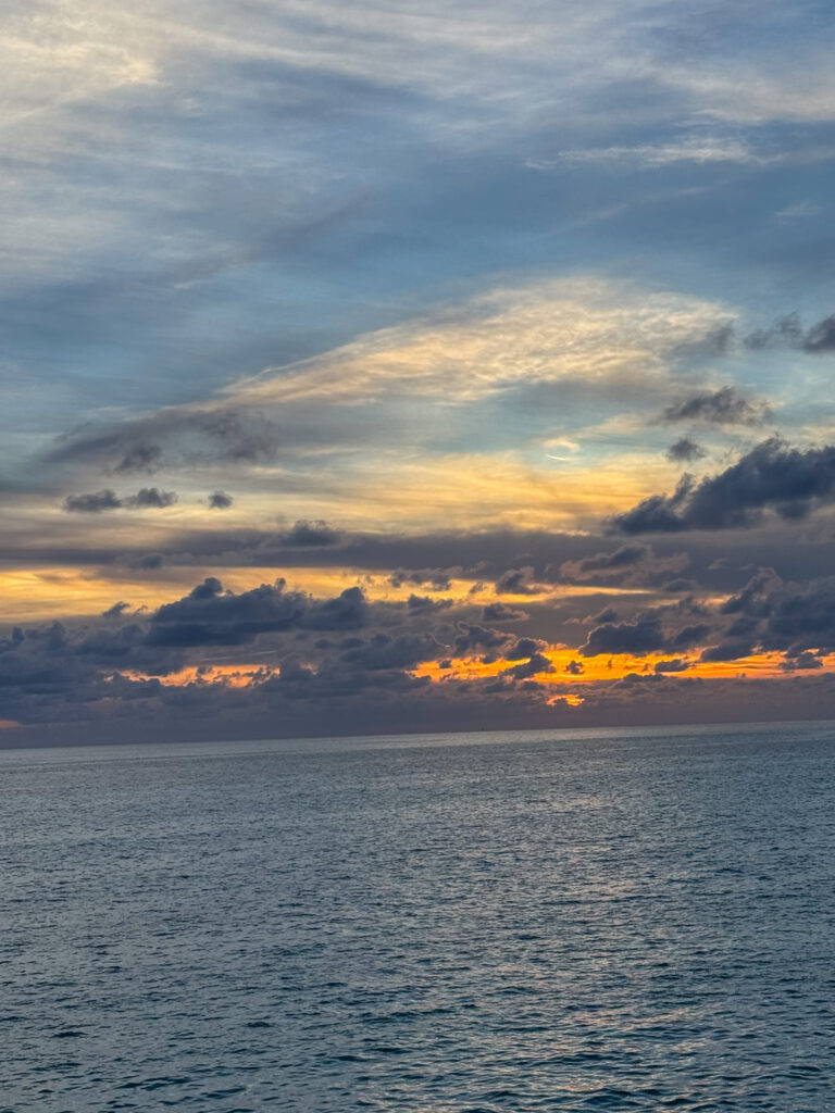Cloud lit gold and grey over a flat sea