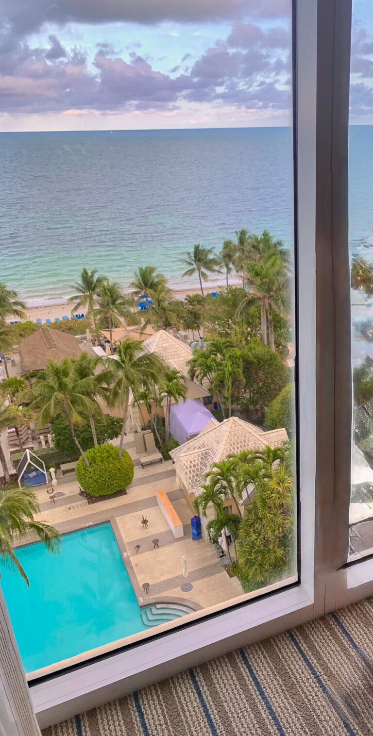 The pool and the beach seen through a window, the timber frame cutting the view