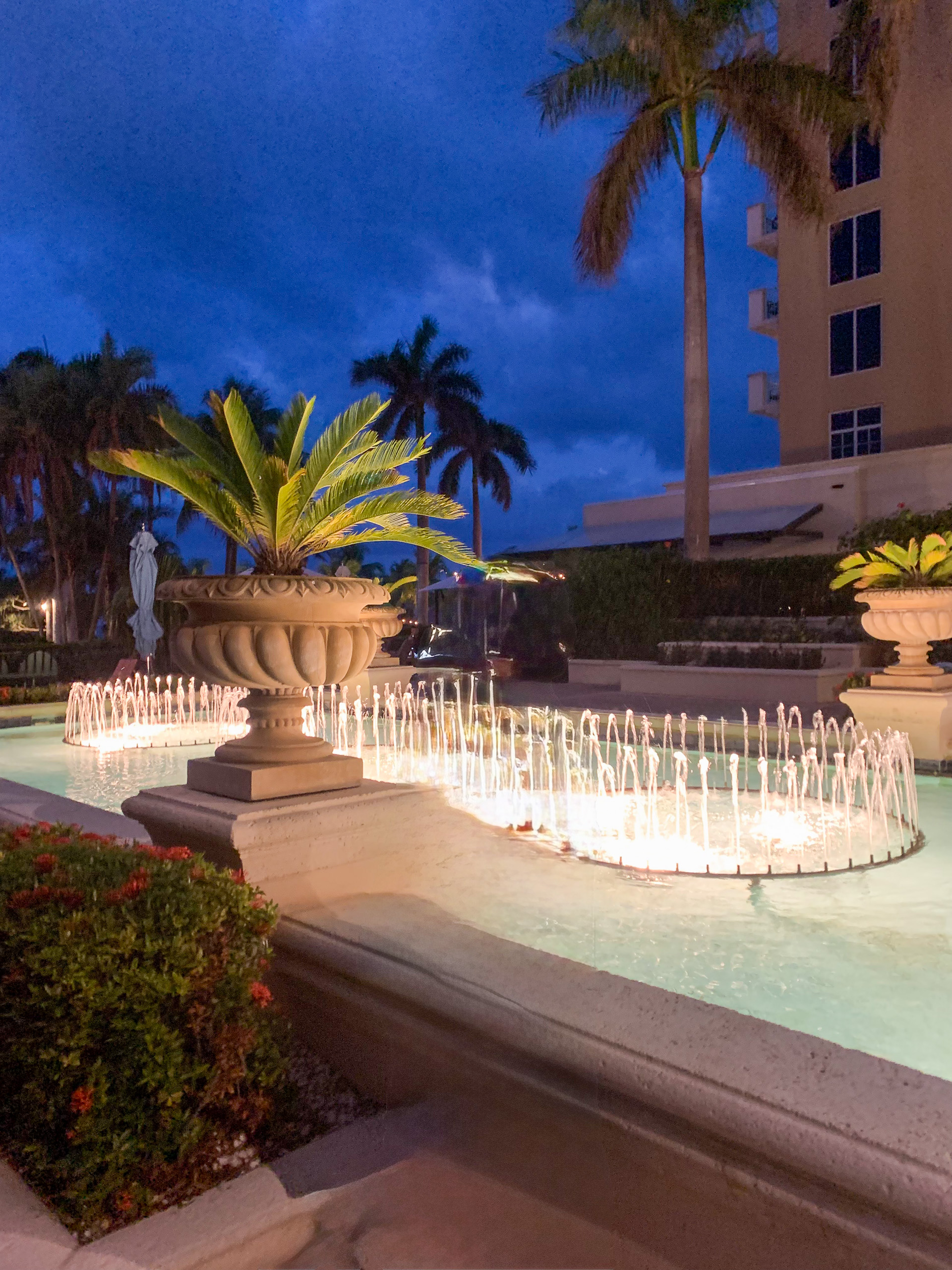 The fountain and the front of the building lit against a deep blue sky