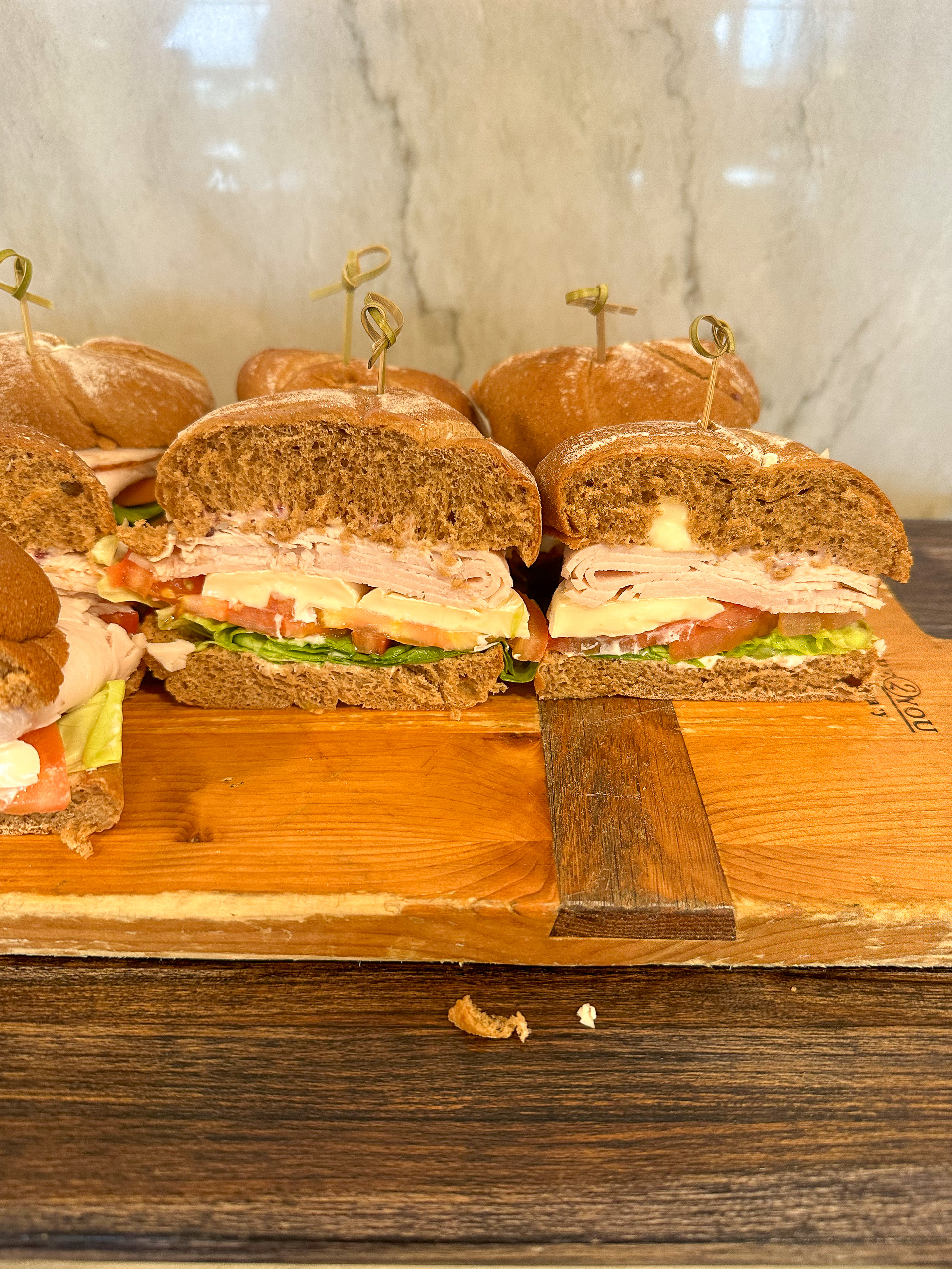 A row of small burgers on a wooden board