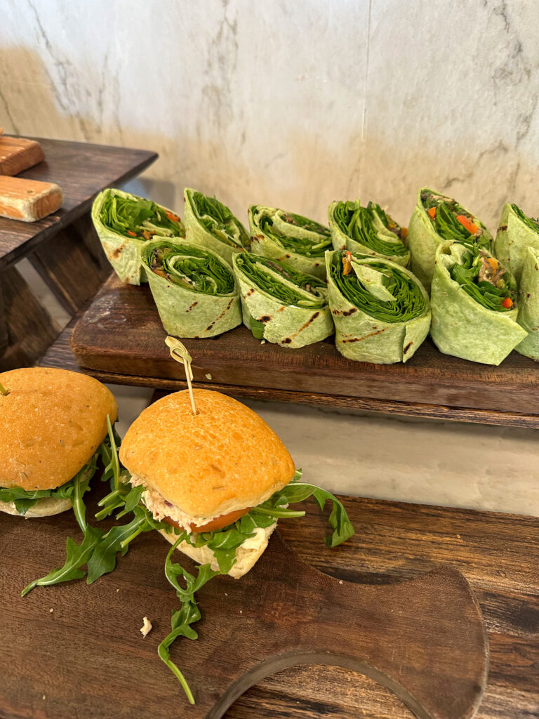 Burgers dressed with avocado and leaves, lined up on the board