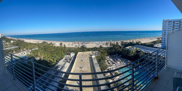 The beach running north from the balcony, the sea flat and pale to the horizon