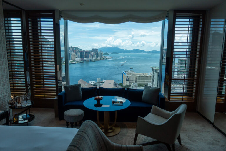 A round blue table at the window with the harbour spread out behind