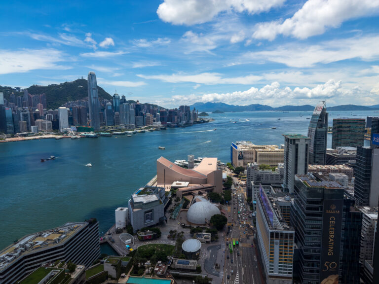 The harbour in full daylight, ferries crossing and the island rising behind