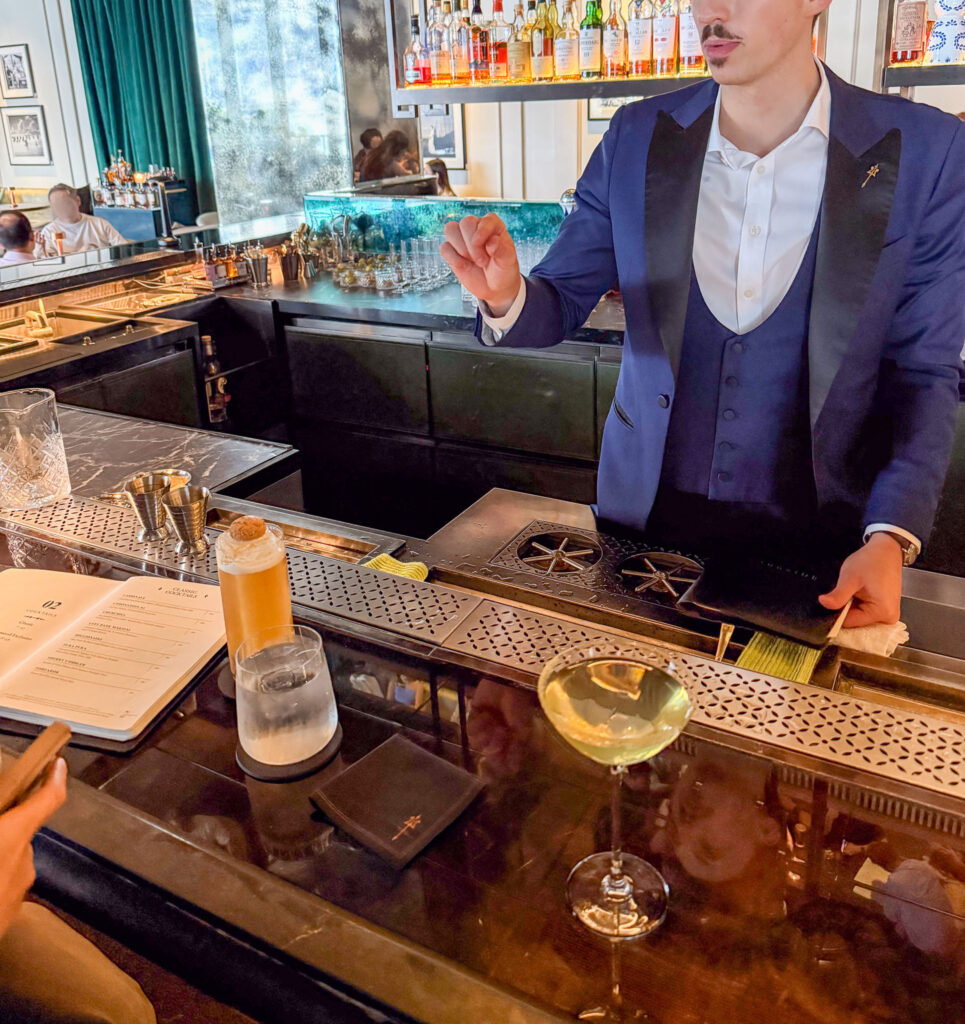 A bartender working behind the counter, bottles and glassware ranged behind