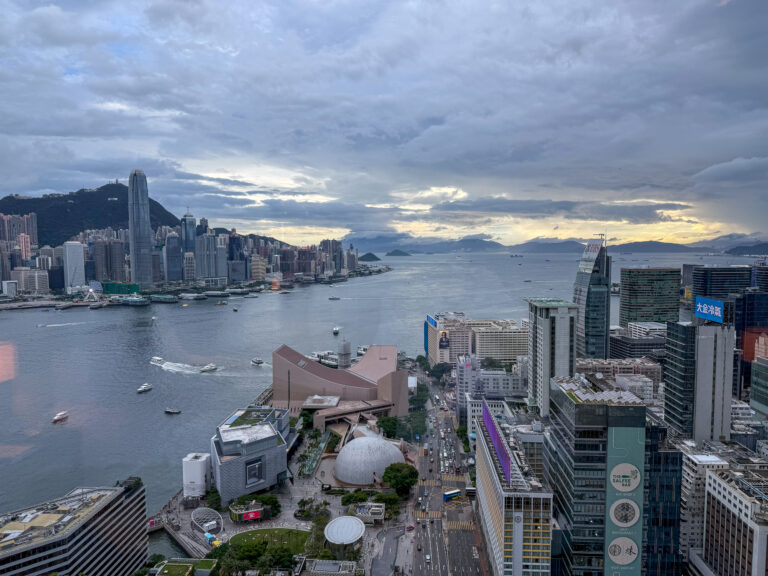 The harbour at dusk under broken cloud, lights coming on across the water