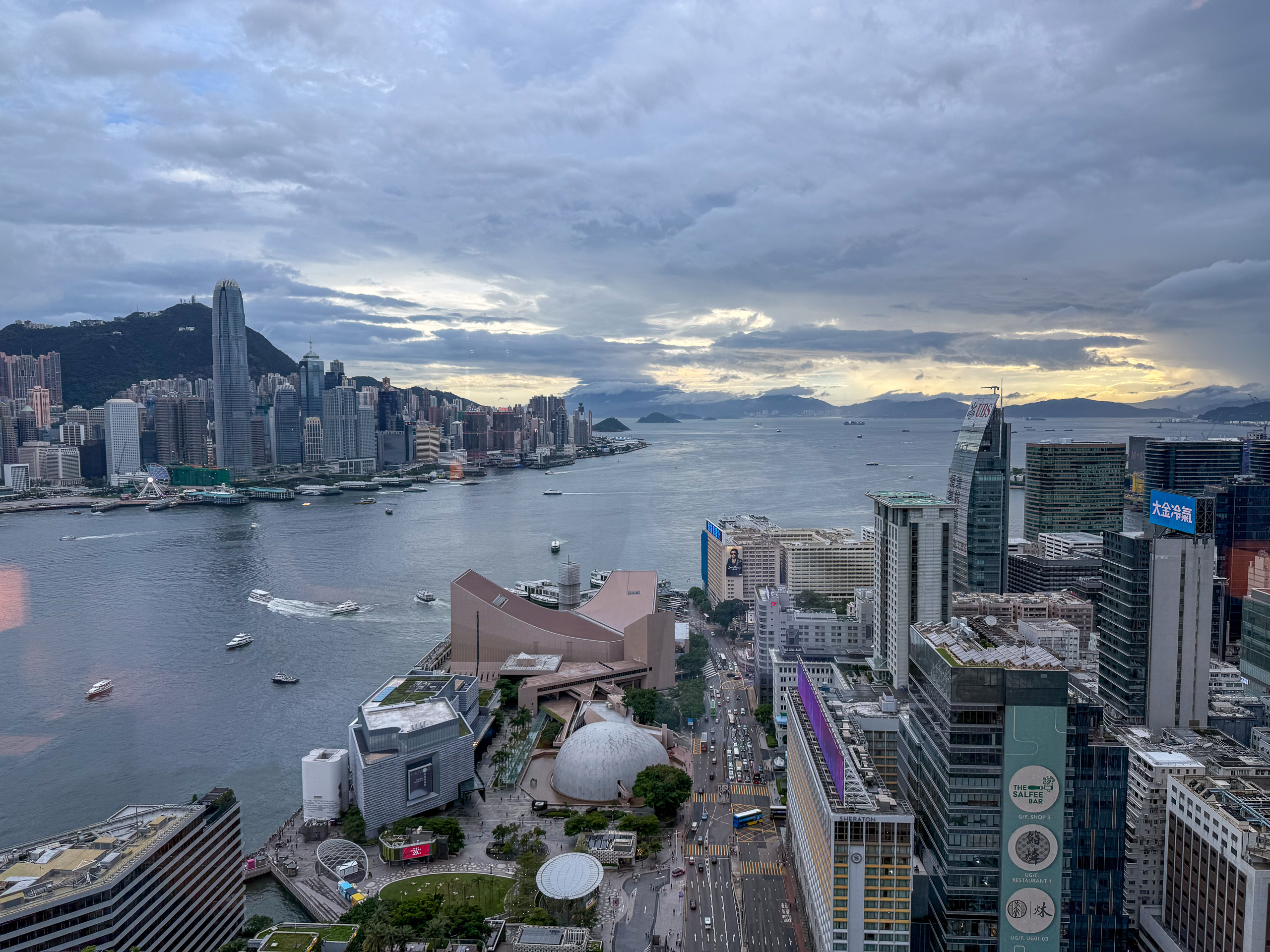 The harbour at dusk under broken cloud, lights coming on across the water