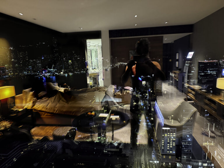 The darkened room reflected in the glass against the city lights