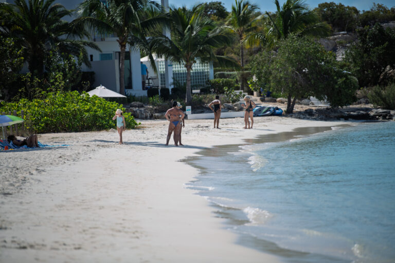 Bathers standing in the shallows along the shore in the afternoon