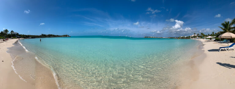 A wide panorama of the bay from the sand, the water almost still