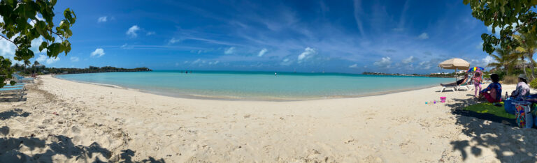 A panorama of the far end of the beach, bathers gathered under the trees