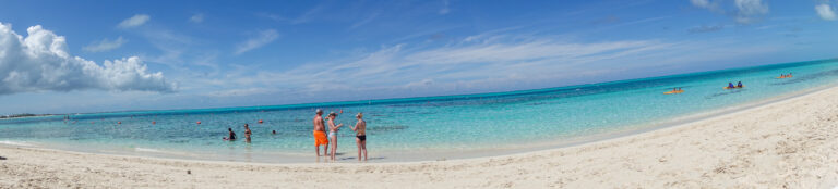 A long panorama of the bay with bathers in the shallows