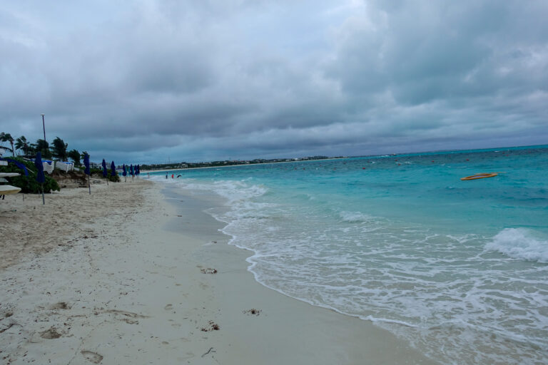 The beach under heavy cloud, the water gone pale and flat