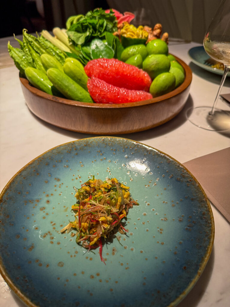 A bowl of raw chillies and vegetables beside the finished dish