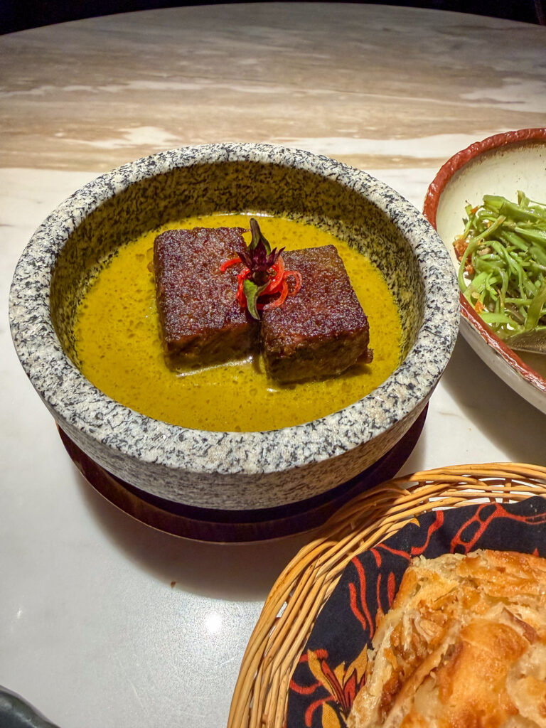 A curry served in a stone bowl beside the basket