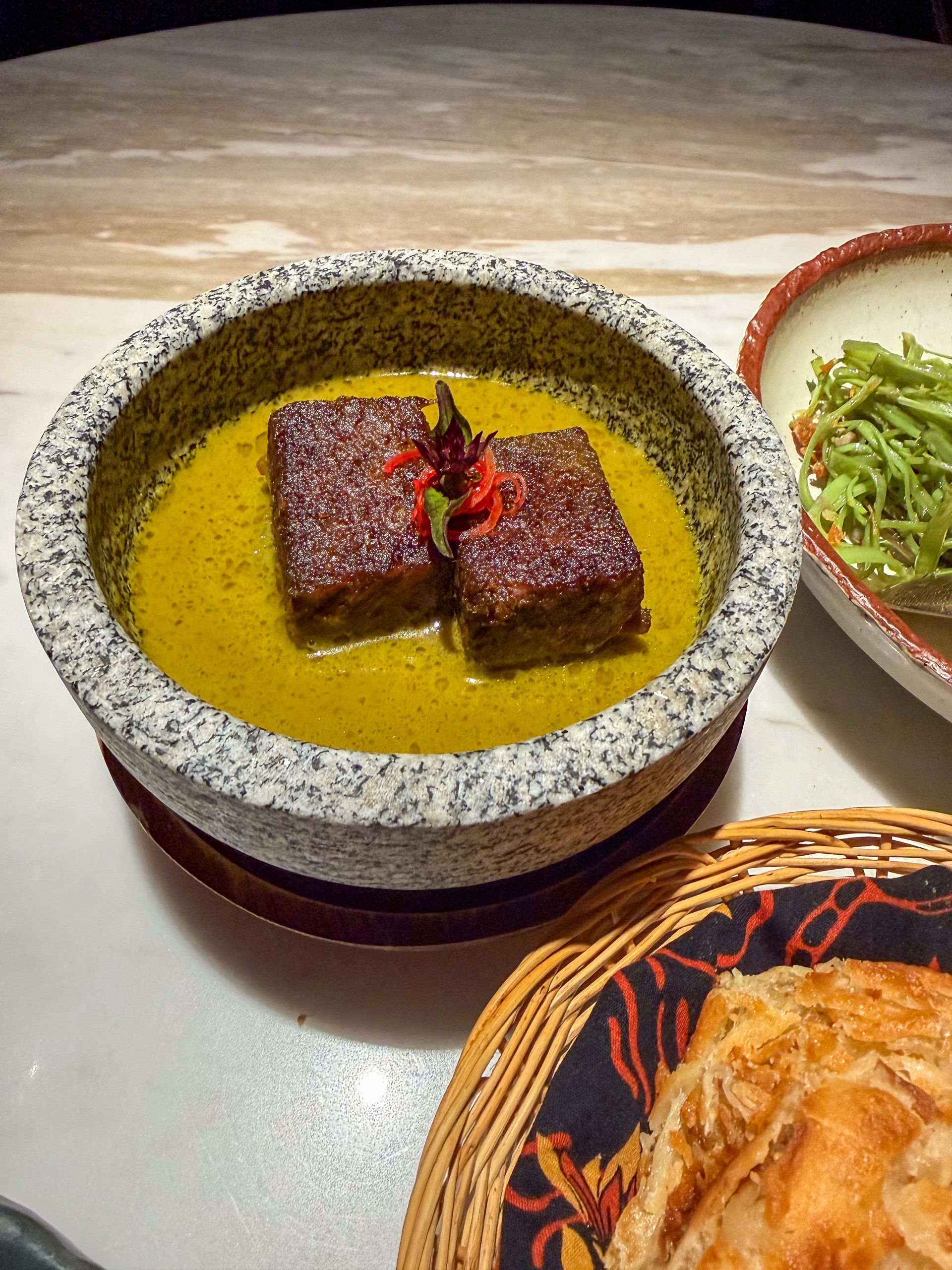 A curry served in a stone bowl beside the basket