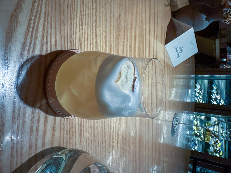 A cocktail under a thick foam cap on the timber bar counter