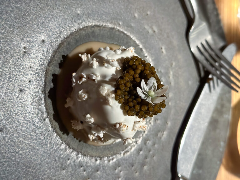 Caviar over cream in a rough stone bowl, a flower set on top