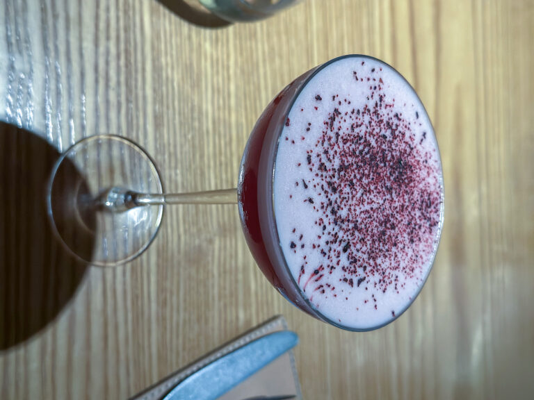 A cocktail under foam dusted deep red, seen from above