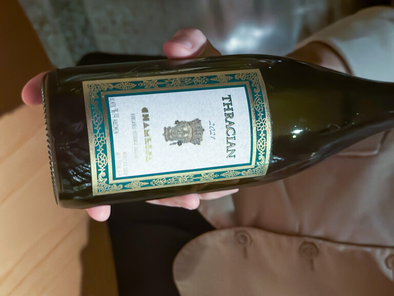 A bottle of Thracian white held across the table